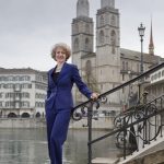 Zurich Mayor Corine Mauch, a woman leader in colorful business attire, on a bike in Zurich.
